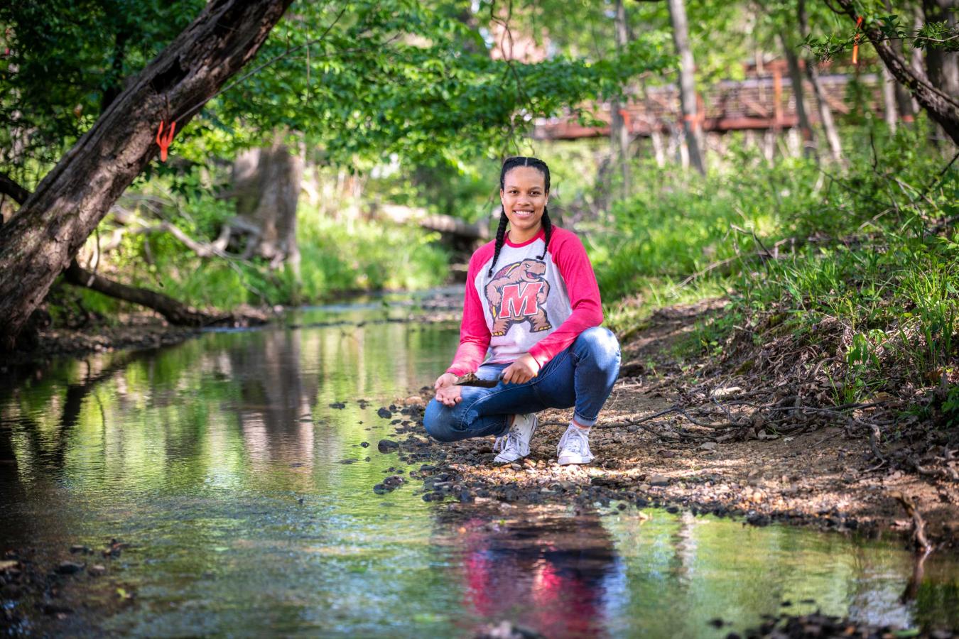 Student at a creek collecting soil samples