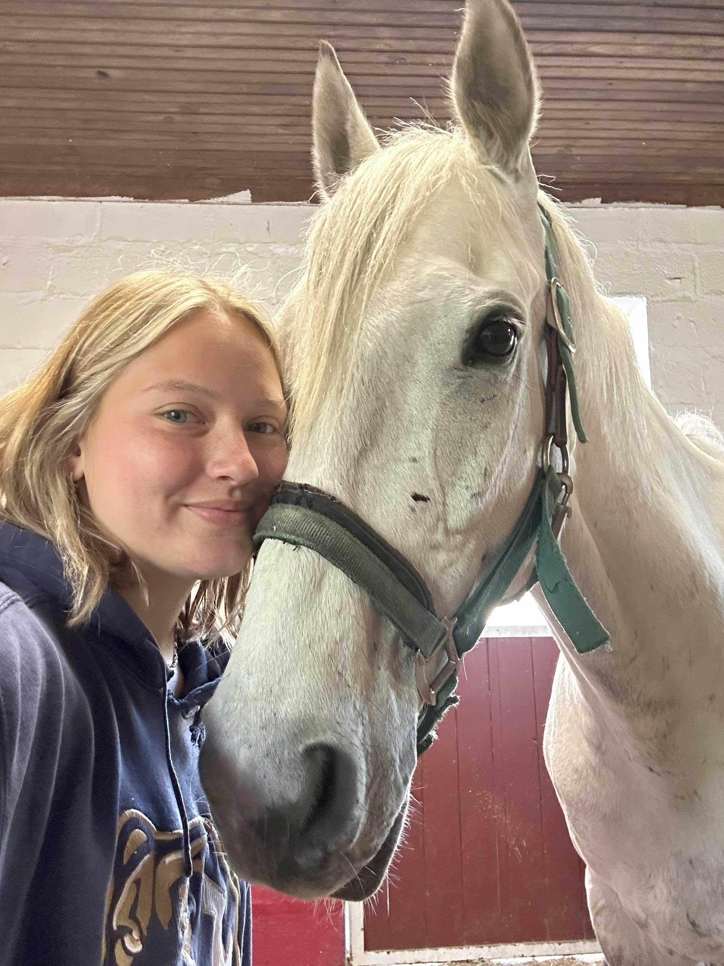 Sweet-natured student nurturing a white horse.