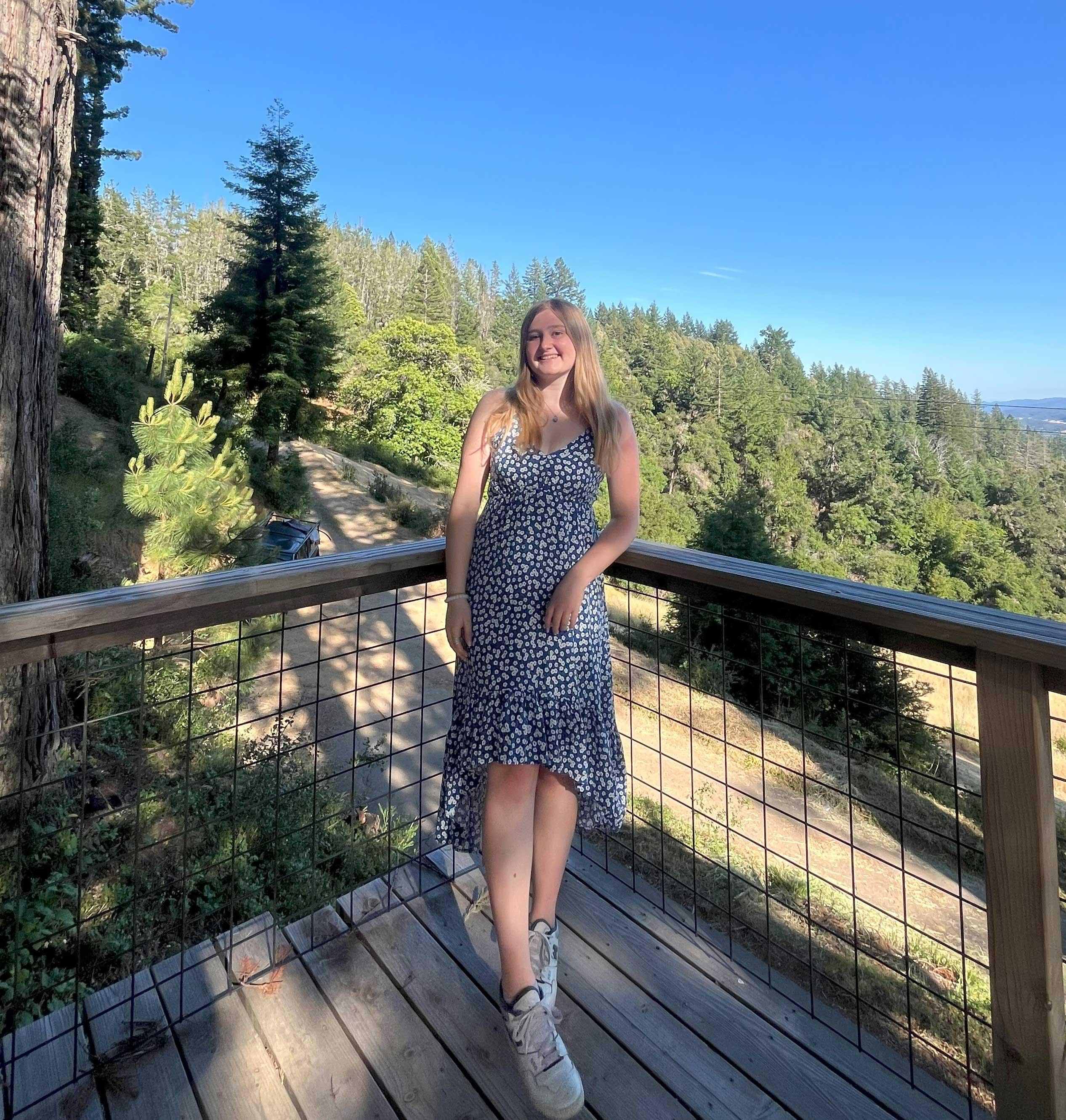 Happy student with the backdrop of a majestic pine forest.