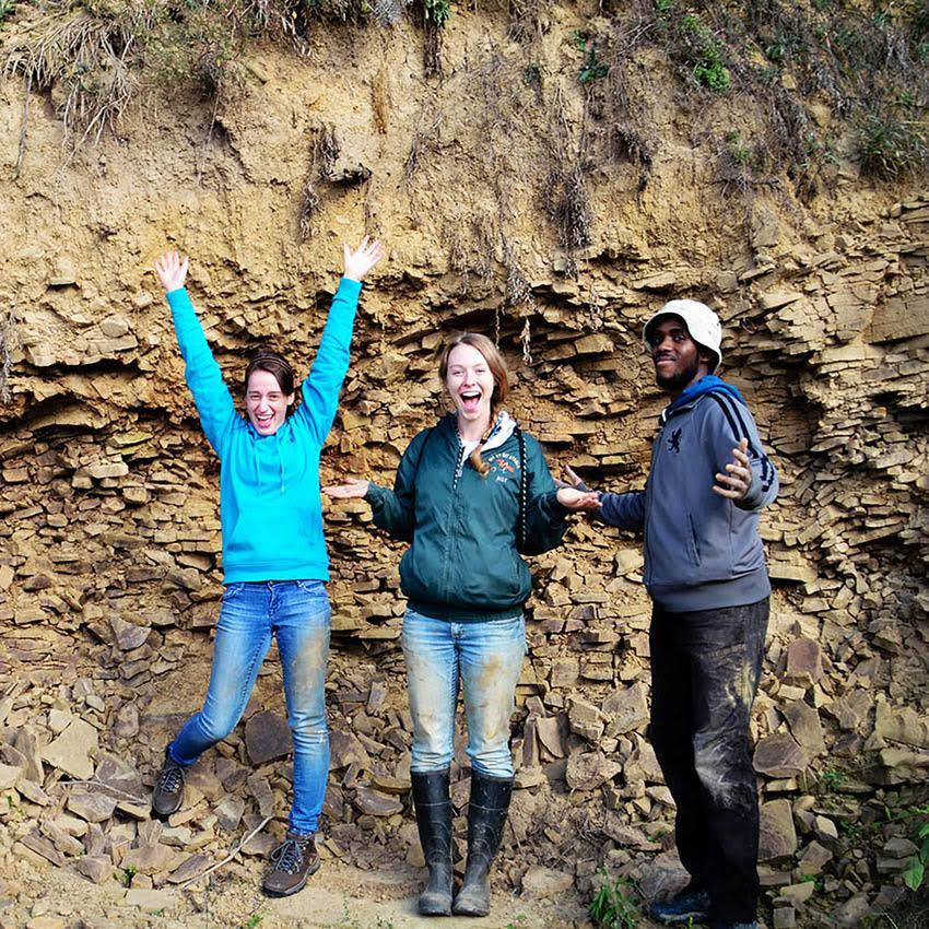 Three people joyfully standing in front of soil and rocks