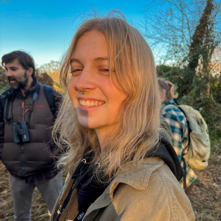 Caroline working in the field, smiling as the sun sets