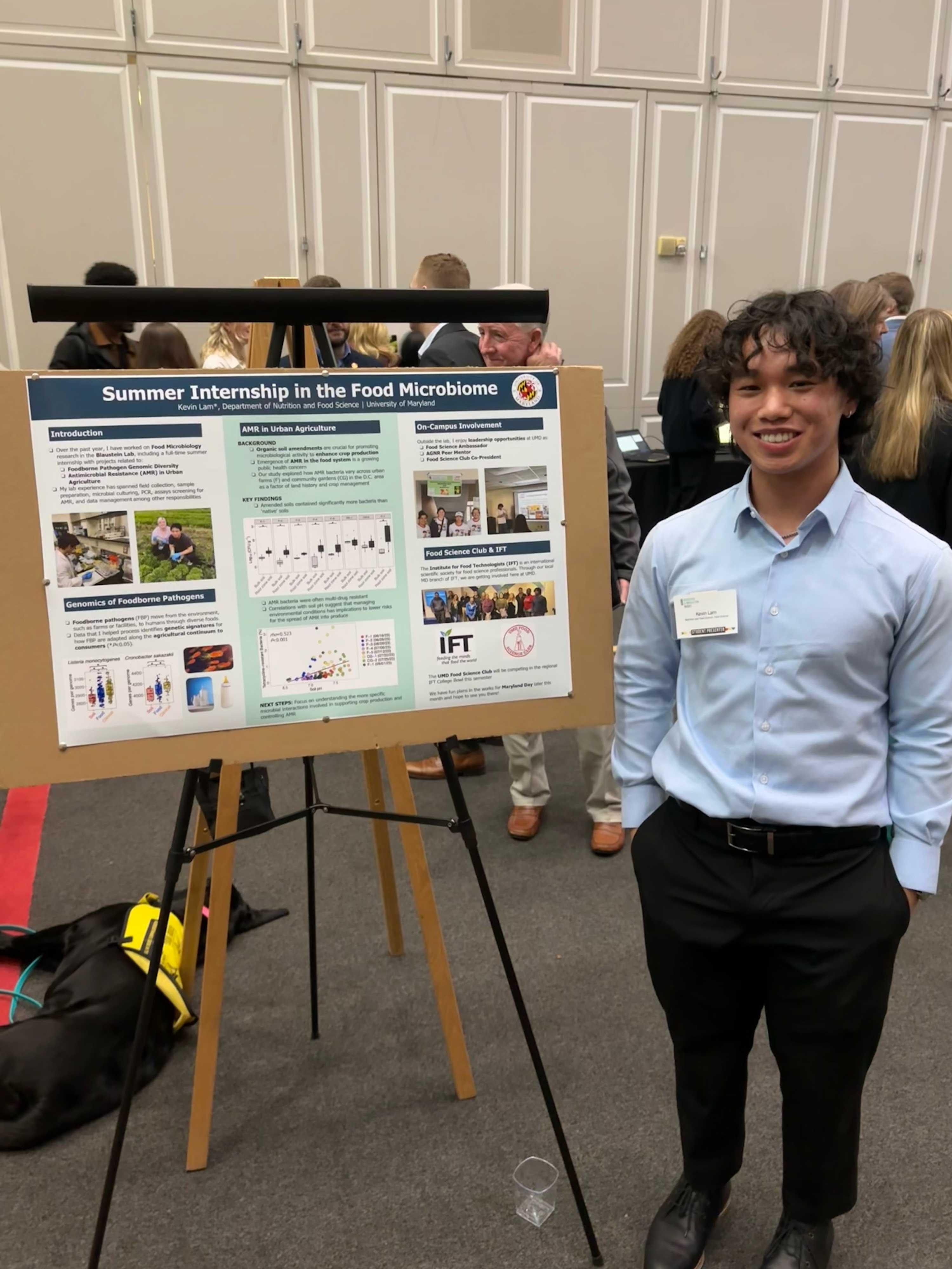 Student proudly displaying scientific poster regarding the food microbiome.