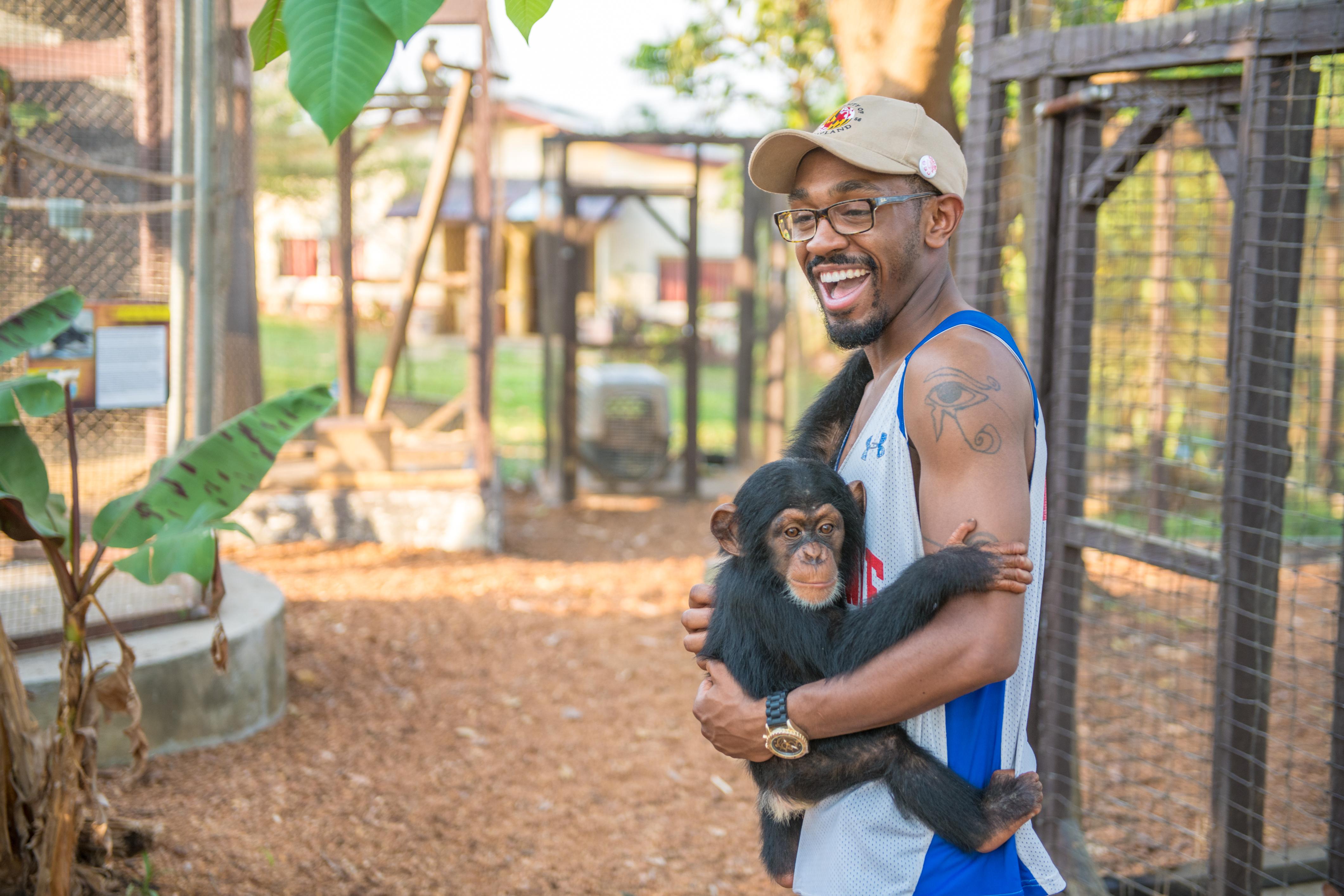 Man smiling at camera while holding a monkey.